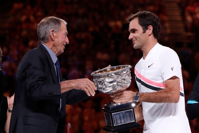 Switzerland's Roger Federer is presented with the trophy by former player Ashley Cooper after winning the 2018 Australian Open final against Croatia's Marin Cilic
