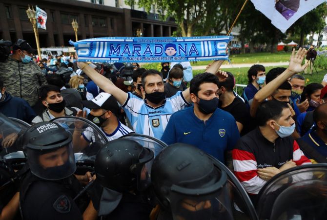 A man holds a scarf as people line up for the wake of soccer legend Diego Maradona 