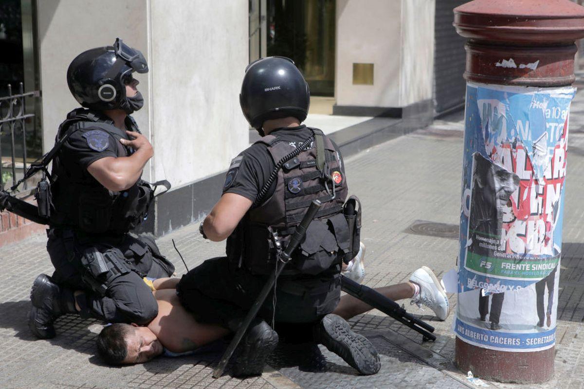 A fan of Diego Maradona is detained by riot police during clashes at the funeral of the football great