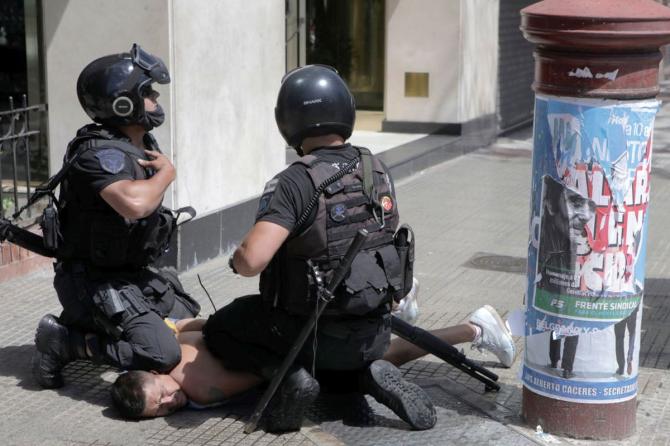 A fan of Diego Maradona is detained by riot police during clashes at the funeral of the football great