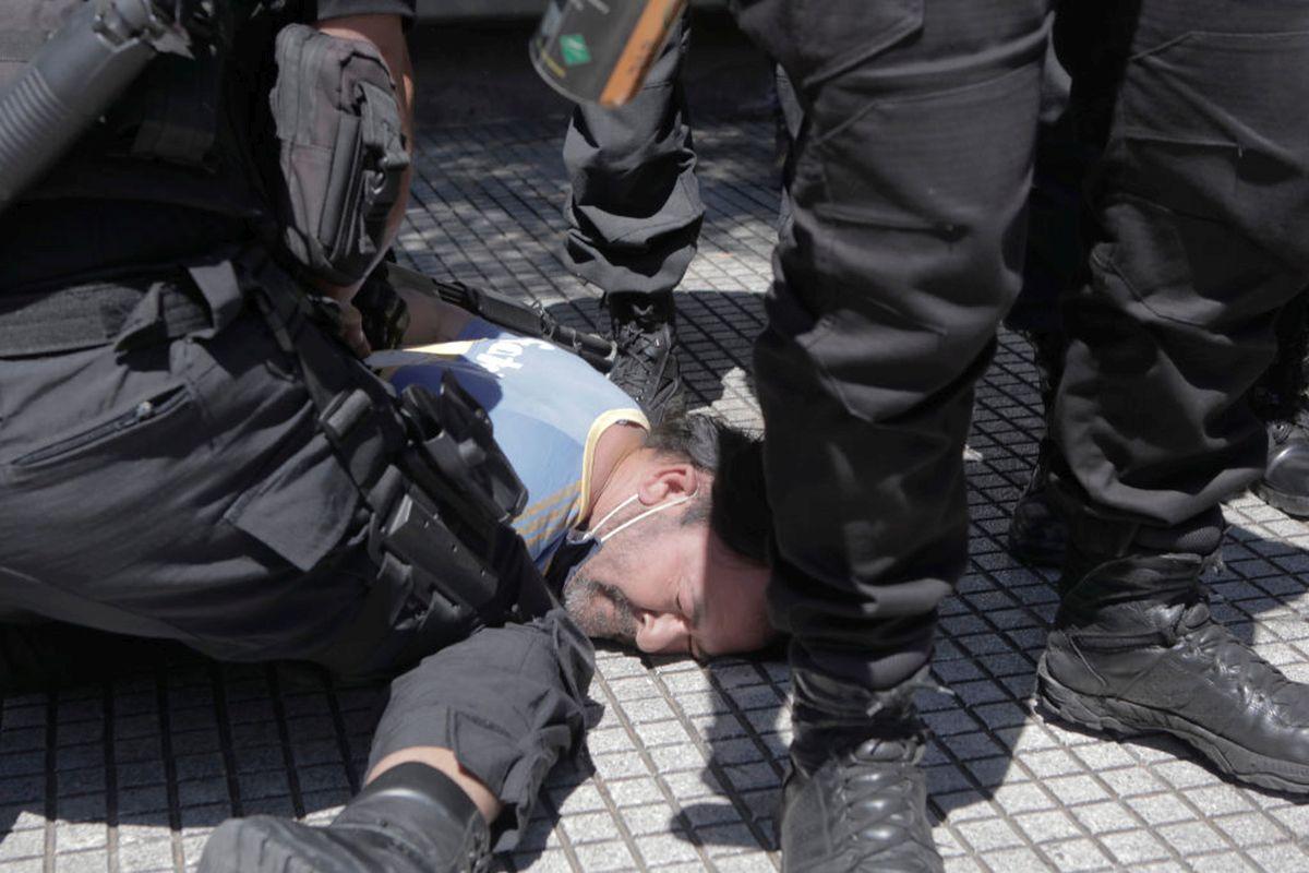 A fan of Diego Maradona is detained by riot police