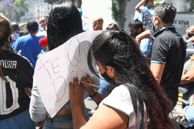 A fan writes a sign while standing in the queue to pay tribute to Diego Maradona who lays in state in the goverment palace Casa Rosada on Thursday
