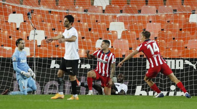 Atletico Madrid's Vitolo and Marcos Llorente celebrate their first goal as Valencia's Jaume Domenech and teammates look dejected on scoring the own goal during their match at Mestalla, Valencia, 