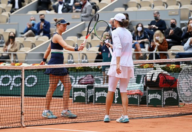 Poland's Iga Swiatek, right, knocks racquets at the net with Argentina's Nadia Podoroska following victory in the semi-finals of the French Open