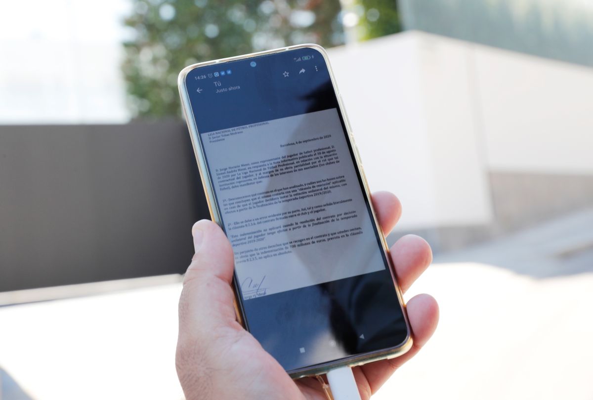 A journalist displays a letter on a mobile phone from Lionel Messi's father and agent Jorge Messi to La Liga President Javier Tebas, outside Messi's home in Barcelona