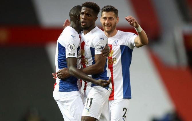 Wilfried Zaha of Crystal Palace celebrates with teammate Cheikhou Kouyate after scoring his team's third goal against Manchester United