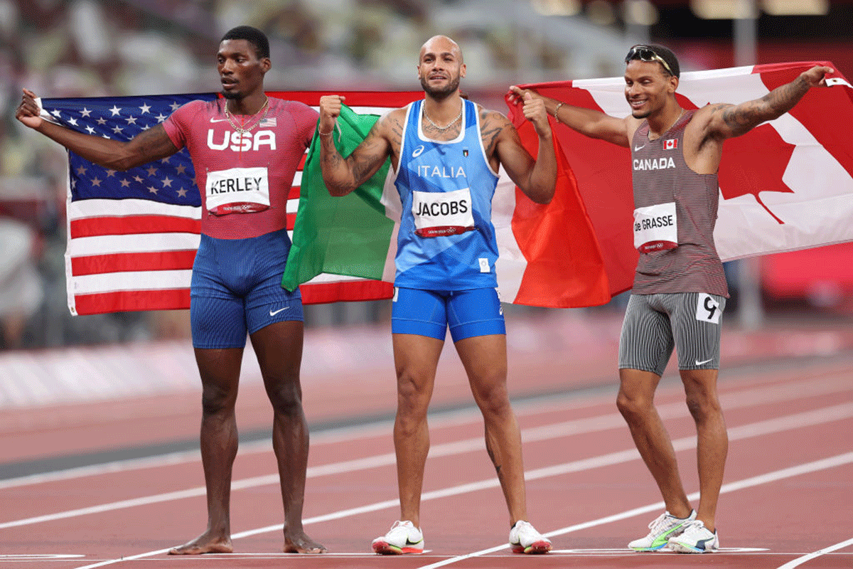 Silver medallist Fred Kerley of United States, gold medallist Lamont Marcell Jacobs of Italy and bronze medallist Andre De Grasse of Canada pose on the track after their Men's 100m final