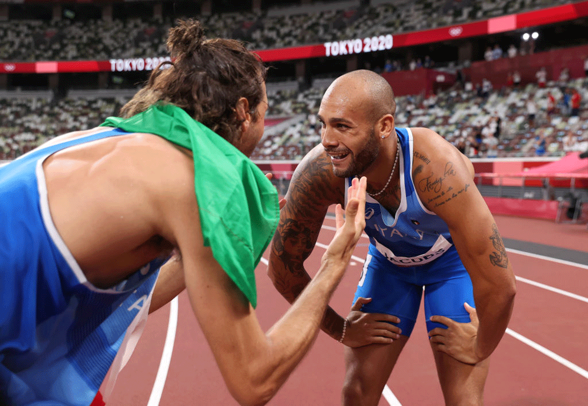 Italy's Lamont Marcell Jacobs is congratulated by teammate Gianmarco Tamberi after winning the Men's 100m final