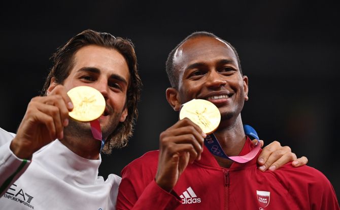 Gold medallists Gianmarco Tamberi of Italy and Mutaz Essa Barshim of Qatar pose with their Olympics high jump as they celebrate on the podium. 