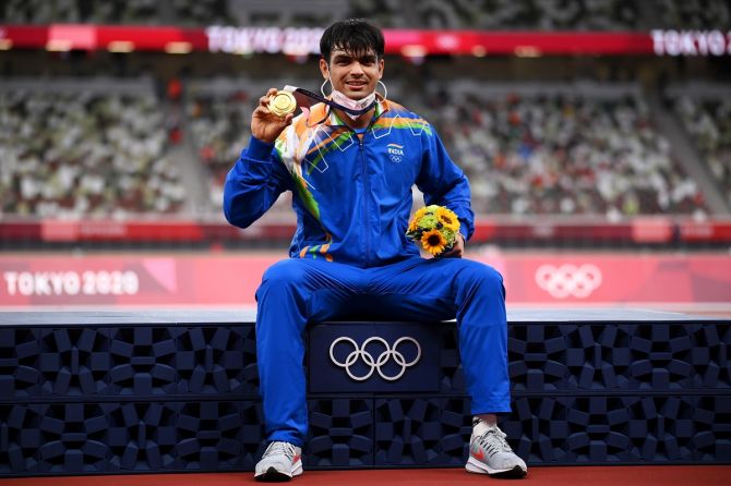 Neeraj Chopra sits on the victory podium and shows off his gold medal after the presentation ceremony.
