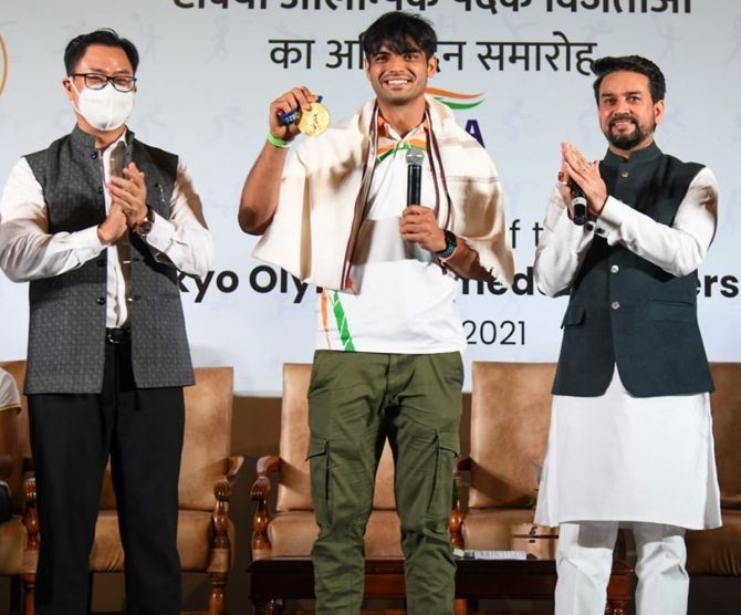 Gold medallist Neeraj Chopra, flanked by Union Minister of Law and Justice Shri Kiren Rijiju, left, and Union Minister of Youth Affairs and Sports Shri Anurag Thakur, proudly displays his gold medal from the men's Javelin Throw at a felicitation function for India's Tokyo Olympics medallists, in New Delhi, on Monday.