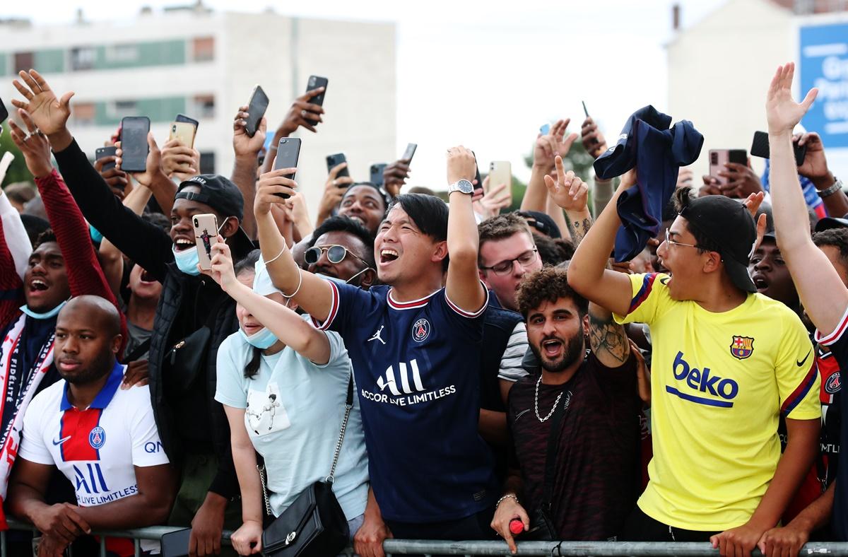 Paris St Germain fans celebrate as Lionel Messi arrives at Paris-Le Bourget airport.  