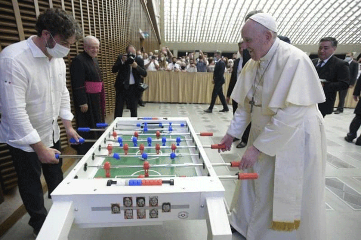 Pope Francis plays a round of foosball on the table gifted to him on Wednesday