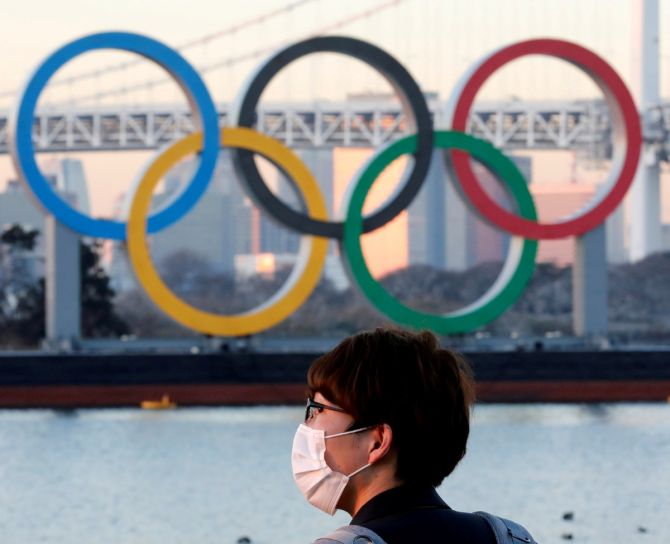 A man wears a protective mask amid the coronavirus outbreak in front of the giant Olympic rings in Tokyo, A man wears a protective mask amid the coronavirus outbreak in front of the giant Olympic rings in Tokyo