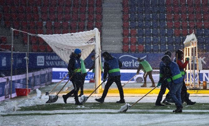 Ground staff work on the pitch to clear snow prior to the La Liga match between Osasuna and Real Madrid.