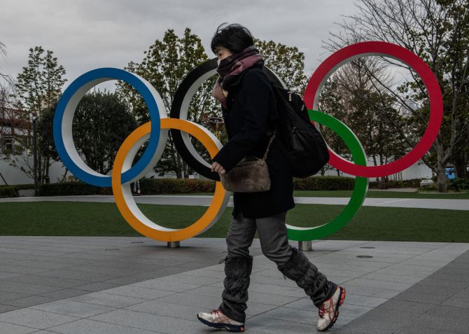 A woman wearing a face mask runs past the Olympic Rings on January 12, 2021 in Tokyo, Japan