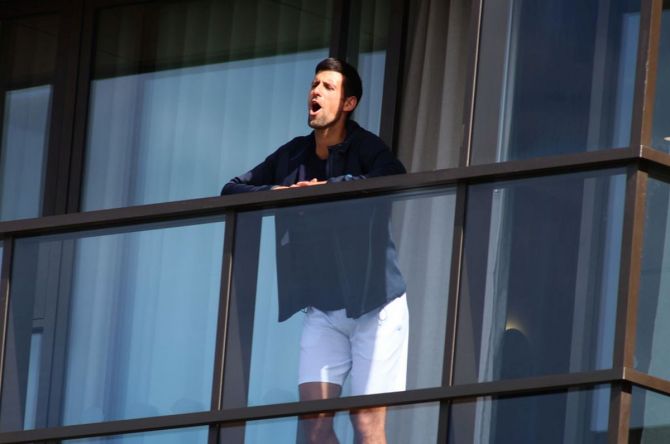 In quarantine, Novak Djokovic looks out of his hotel balcony at M Suites, in North Adelaide, in Adelaide on Thursday. His quarantine is set to end on Thursday.