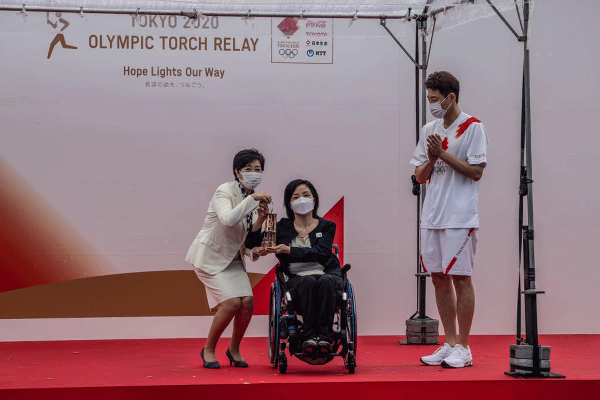 Tokyo Governor Yuriko Koike (left) holds the Olympic torch in a lantern during an unveiling ceremony for the Tokyo leg of the Olympic torch relay with Aki Taguchi, official ambassador of the Tokyo 2020 torch relay (centre), and Shuzo Matsuoka, the first torch bearer for the Tokyo relay, in Komazawa Olympic Stadium in Tokyo, Japan, on Friday, July 9.