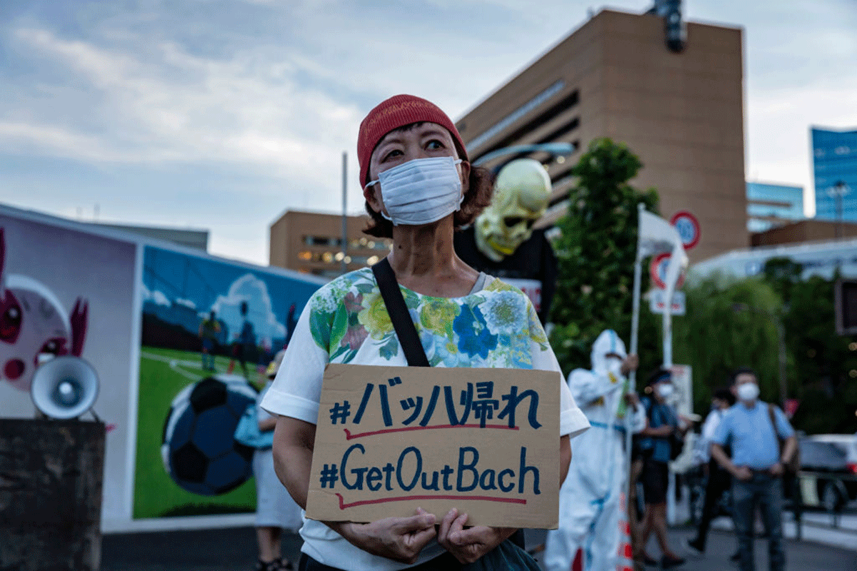 A woman holding a placard marches during a demonstration against the forthcoming Tokyo Olympic Games 