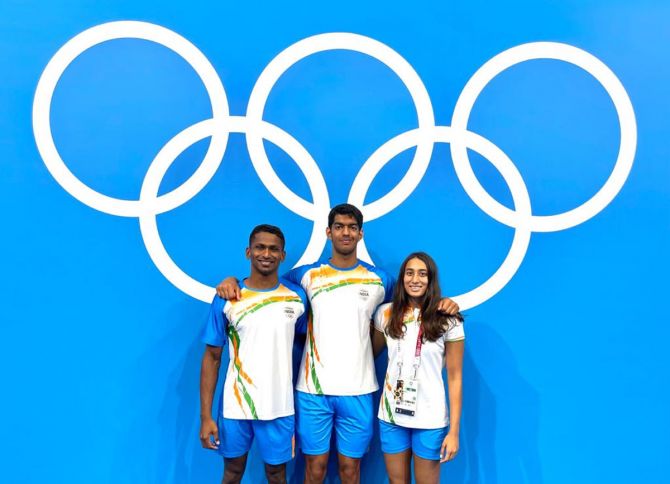 India's swimmers Sajan Prakash, Srihari Nataraj and Maana Patel pose in front of the Olympic rings at the Games Village in Tokyo