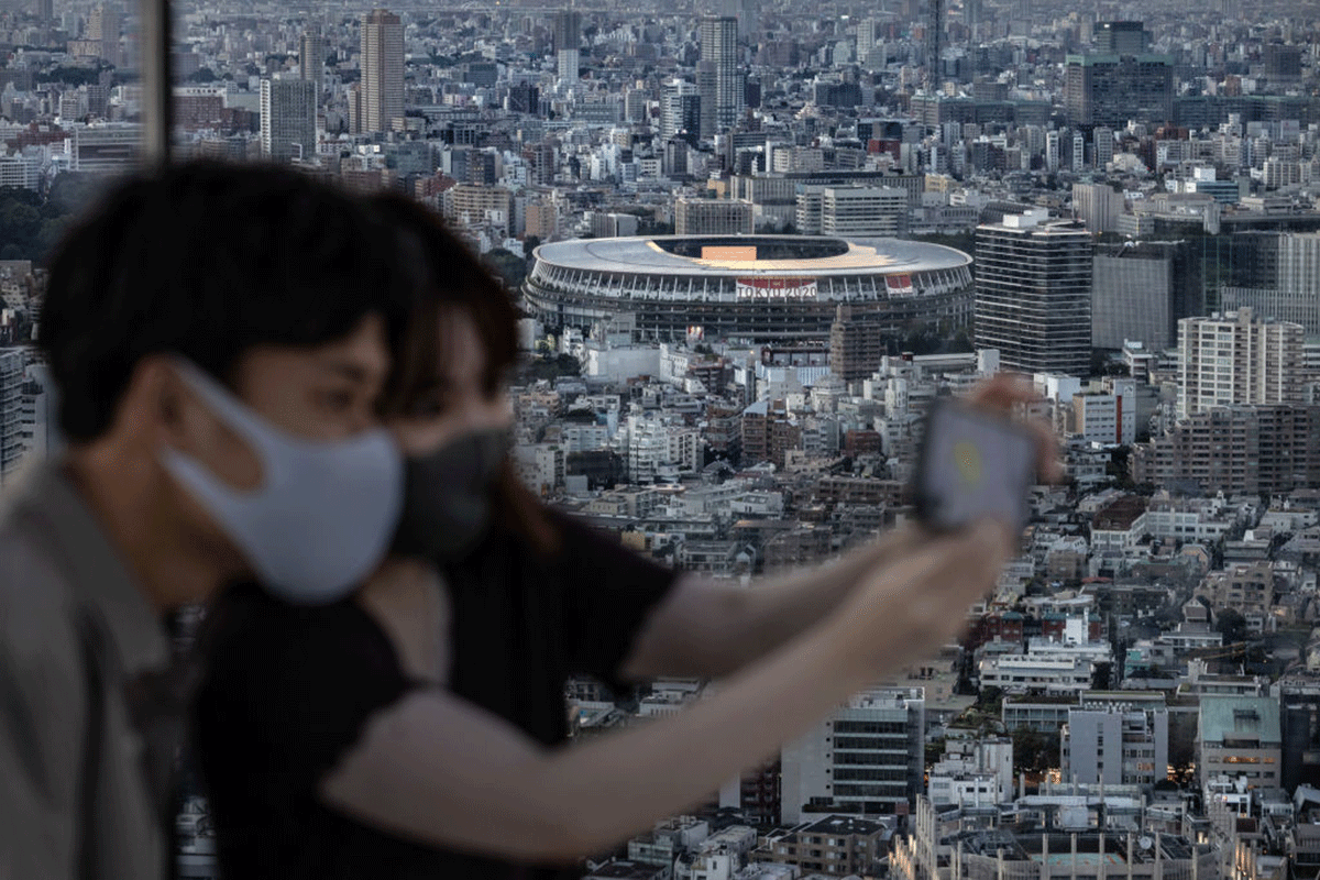 Tokyo Olympic Stadium is pictured in the background as a couple take a selfie on Shibuya Sky Deck in Tokyo on Thursday. Located in the "Ring of Fire" arc of volcanoes and oceanic trenches encircling the Pacific Basin, Japan accounts for about 20% of the world's earthquakes of magnitude 6.0 or greater. On average, it experiences a quake every five minutes. 