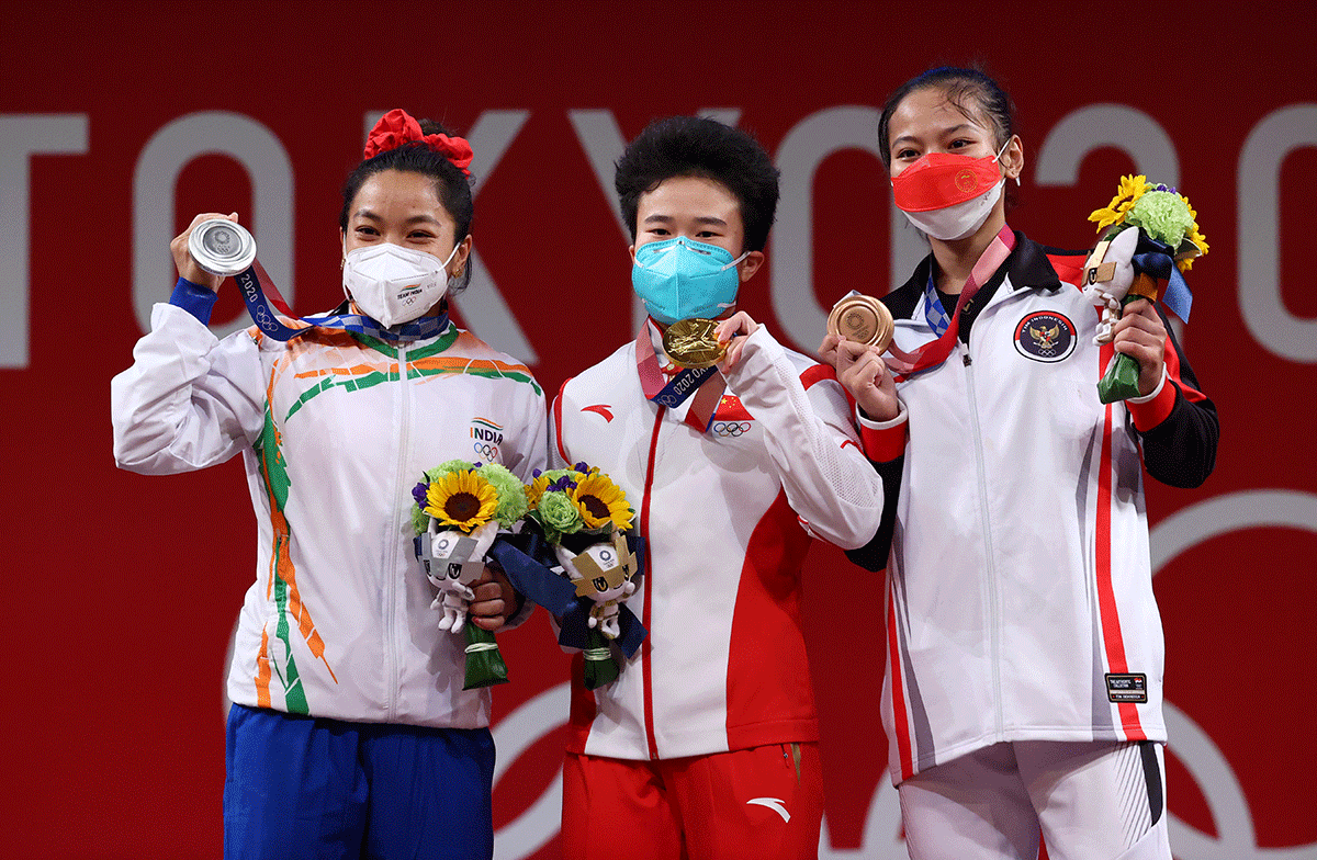 Weightlifting women's 49kg gold medalist Hou Zhihui of China is flanked by silver medalist Mirabai Chanu Saikhom of India and bronze medalist Windy Cantika Aisah of Indonesia during the medal ceremony on the podium on Saturday