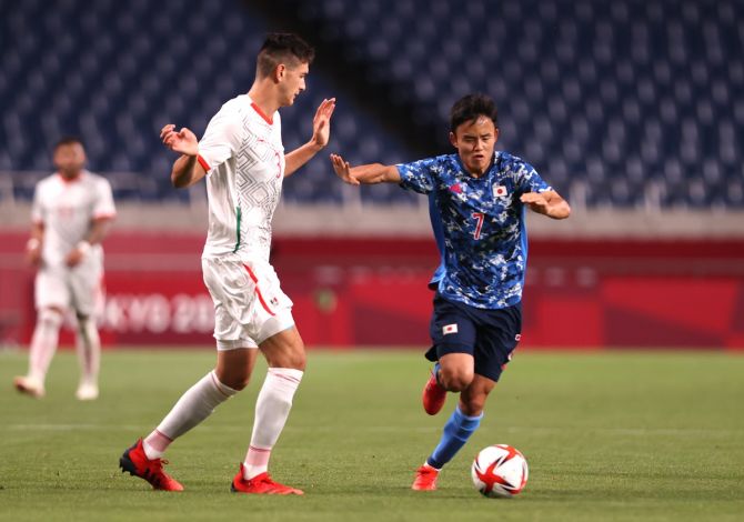 Japan's Takefusa Kubo tries to get past Mexico's Cesar Montes during the men's first round Group A football match at the Tokyo Olympics, at Saitama stadium in Saitama, on Sunday