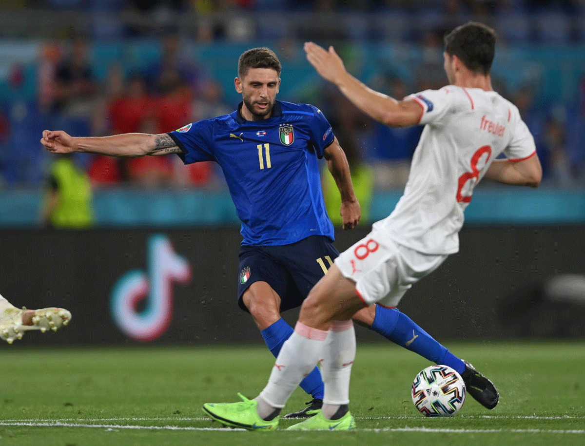 Italy's Domenico Berardi is challenged by Remo Freuler of Switzerland.