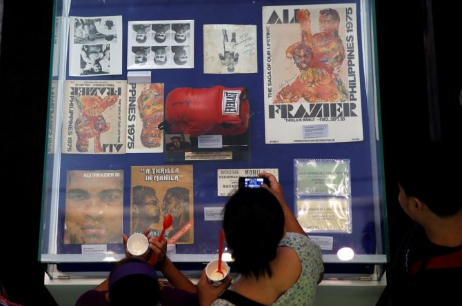 A fan uses a mobile phone to take pictures of late boxer Muhammad Ali's memorabilias of the 1970 bout with Joe Frazier, dubbed as "Thrilla in Manila", in Cubao Quezon City, Metro Manila, Philippines, June 10, 2016