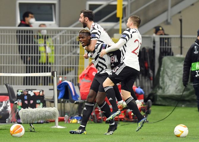 Paul Pogba celebrates scoring with Bruno Fernandes and Luke Shaw after scoring for Manchester United against AC Milan.