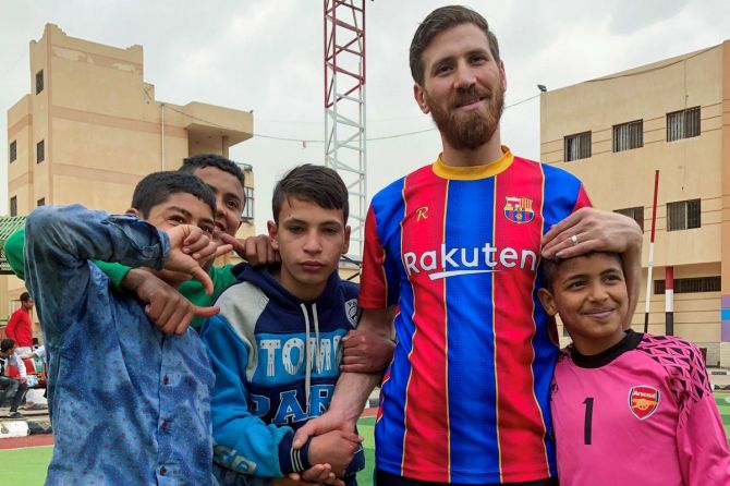 Islam Mohammed Ibrahim Battah, an Egyptian with a striking resemblance to Barcelona's forward Lionel Messi, poses for a photograph with orphaned boys, in the Nile Delta city of Zagazig, north of Cairo, Egypt on Tuesday