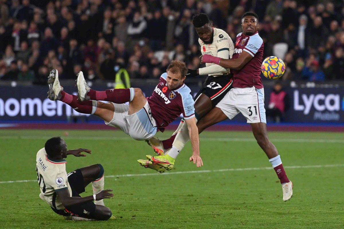Liverpool's Divock Origi heads the ball while challenged by West Ham United's Vladimir Coufal and Ben Johnson