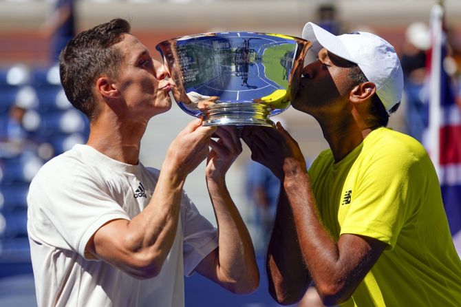 Men's doubles champions Joe Salisbury, left, and Rajeev Ram pose with the trophy after defeating Bruno Soares and Jamie Murray in the US Open men’s doubles final on Friday.