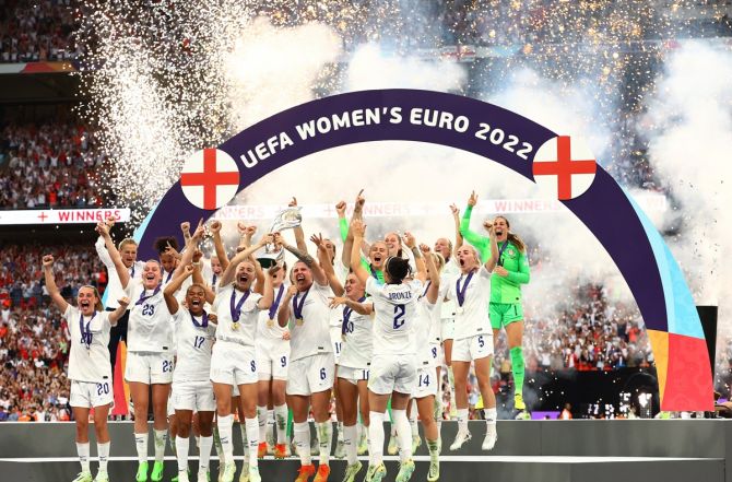 England's Leah Williamson and Millie Bright lift the trophy as the team celebrates vcitory.