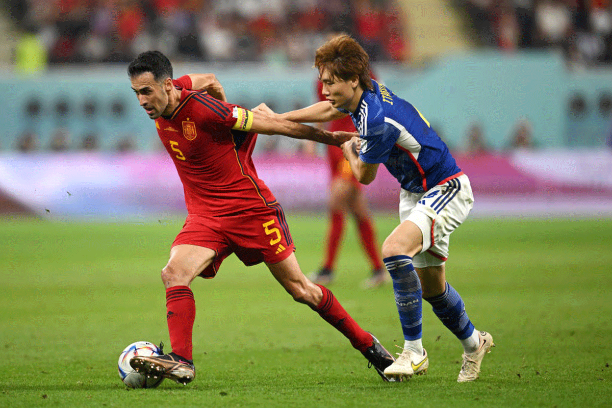 Spain's Sergio Busquets wins the ball against a challenge from Japan's Kou Itakura