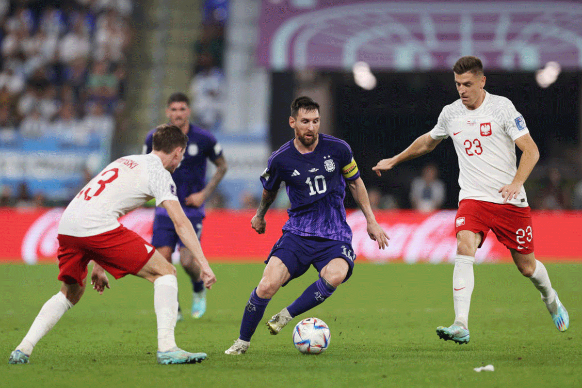 Argentina's Lionel Messi controls the ball as he marked by Poland's Jakub Kaminski (left) and Krzysztof Piatek
