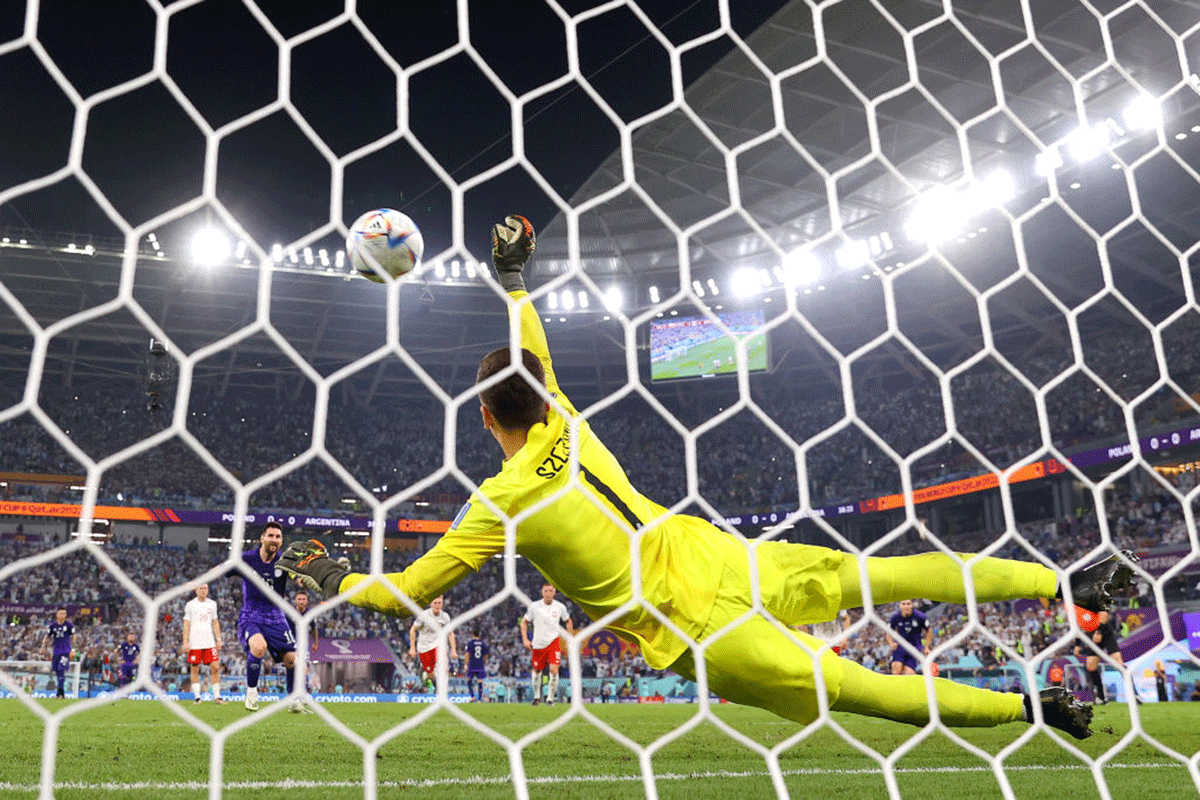 Poland keeper Wojciech Szczesny dives to save a penalty by Argentina's Lionel Messi.