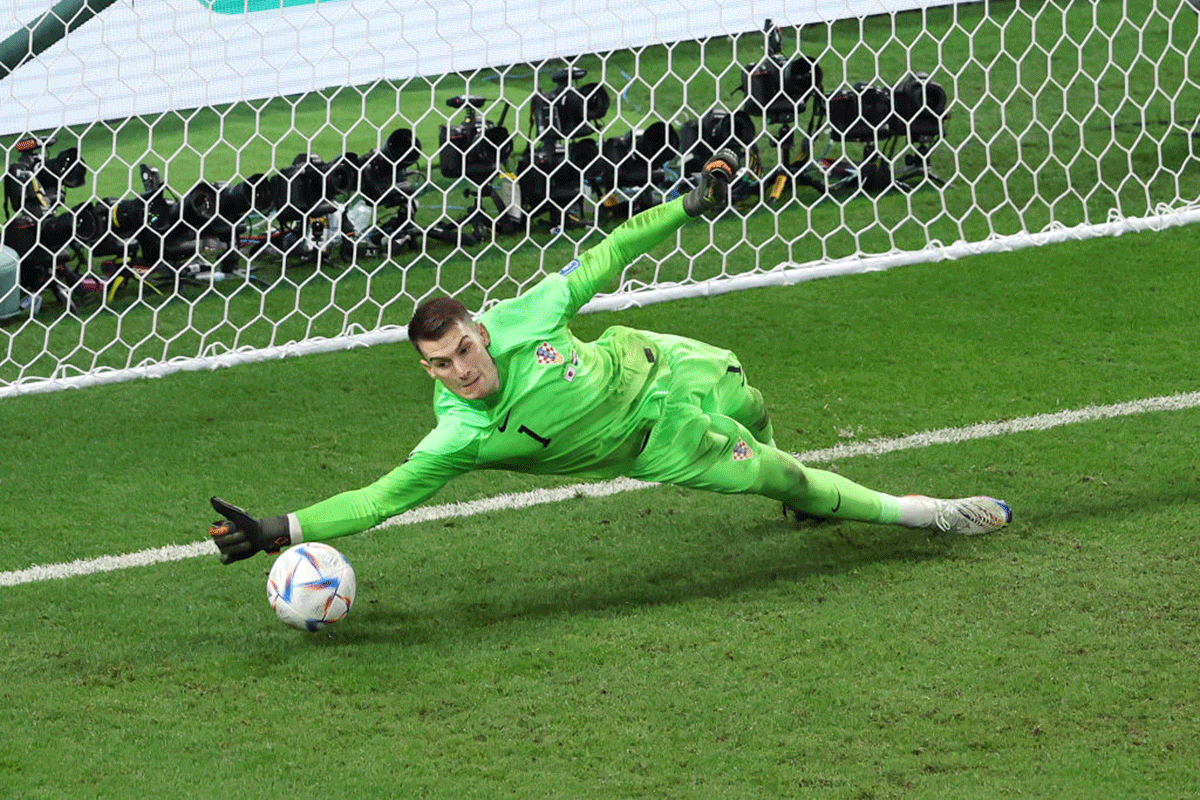 Croatia 'keeper Dominik Livakovic dives to save the second penalty off the boot of Japan's Kaoru Mitoma. 