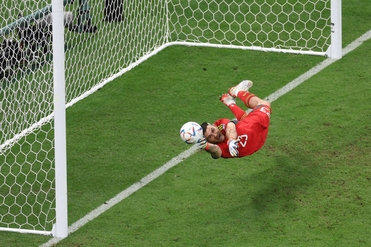 Argentina's Emiliano Martinez dives to save the first penalty taken by Netherlands' Virgil Van Dijk