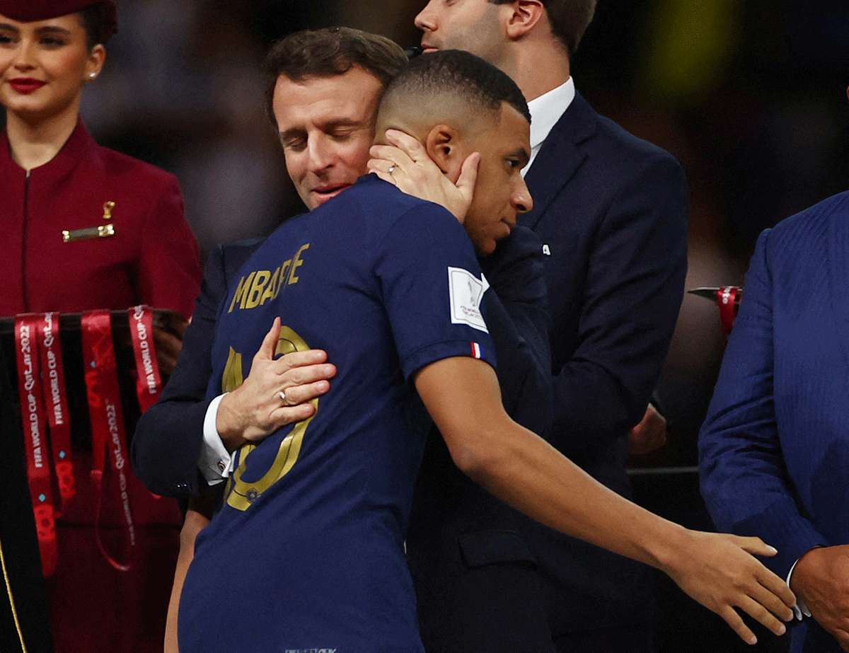 France's Kylian Mbappe is embraced by French President Emmanuel Macron during the trophy ceremony 
