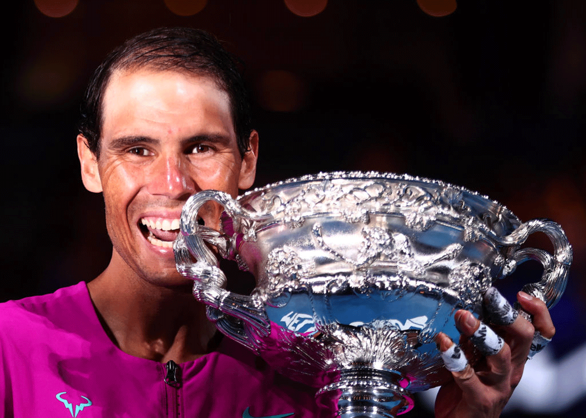 Spain's Rafael Nadal bites the Norman Brookes Challenge Cup as he celebrates victory over Daniil Medvedev to win the 2022 Australian Open and his 21st Grand Slam at Melbourne Park on Sunday 