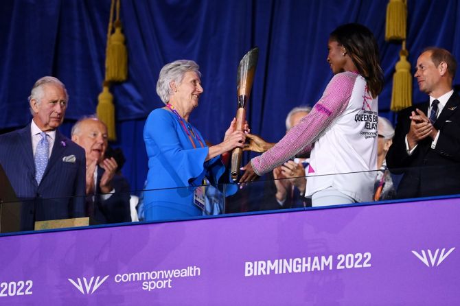 Former track and field athlete Denise Lewis, who won gold in heptathlon at the 2000 Sydney Olympics and was twice Commonwealth Games champion, hands over the Queen’s Baton to Dame Louise Martin. 