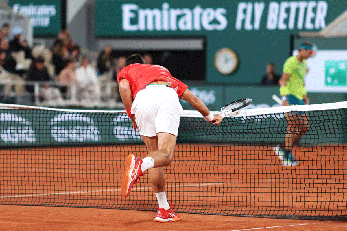 Novak Djokovic slams his racquet against the net