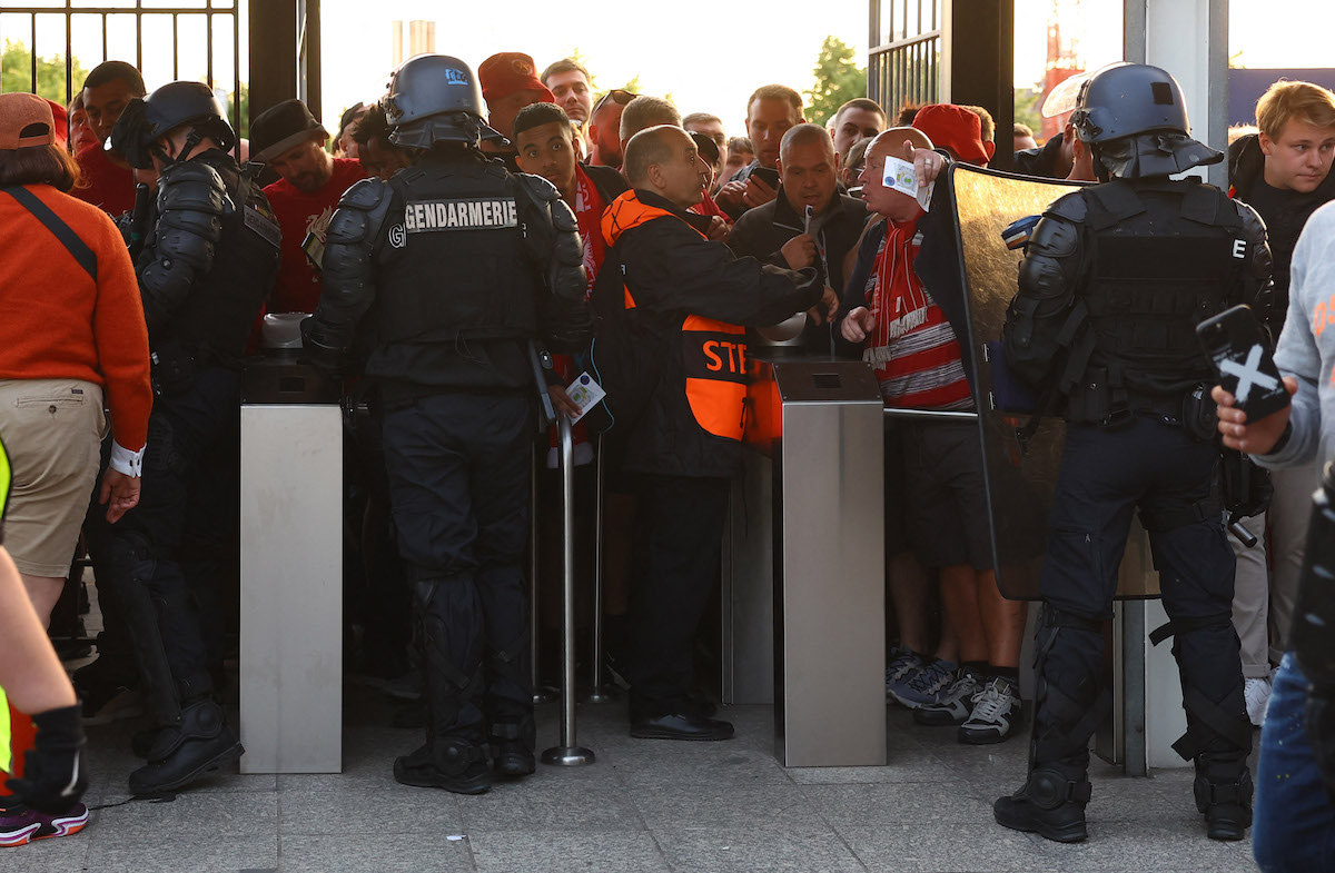 Fans, stewards and police officers by the turnstiles inside the stadium as the match is delayed