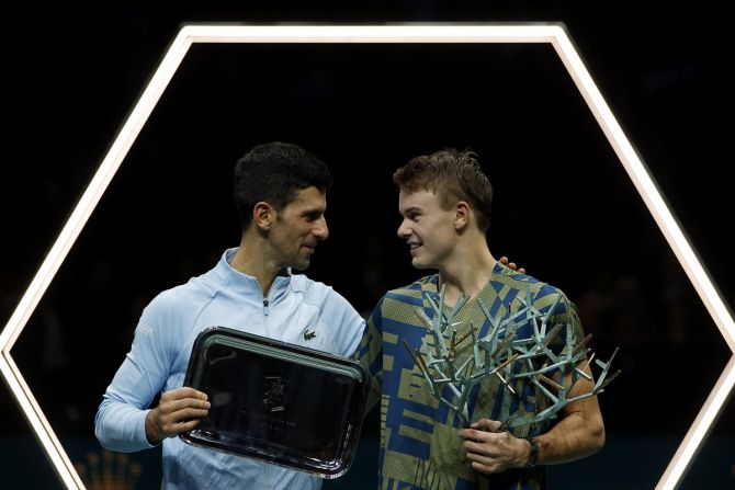 Holger Rune, with the winner's trophy, and Novak Djokovic, with the runners-up plaque, pose for a picture.