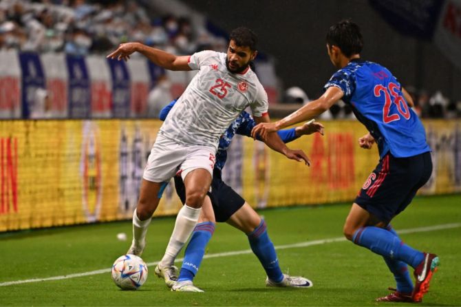 Tunisia's Anis Ben Slimane controls the ball under pressure from Japan's Daichi Kamada and Hiroki Ito.