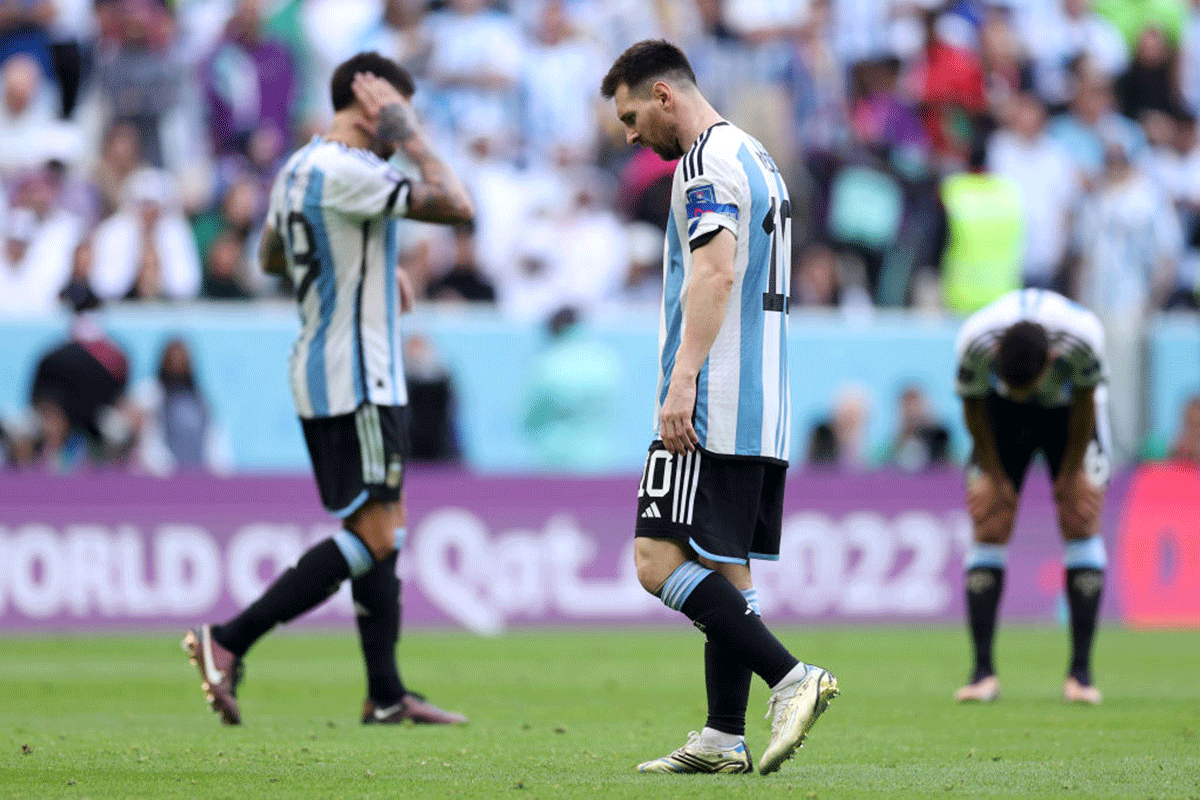 Argentina's Lionel Messi and teammates (in background) look dejected following their side's defeat to Saudi Arabia in their FIFA World Cup Group C match at Lusail Stadium  in Lusail City, Qatar, on Tuesday