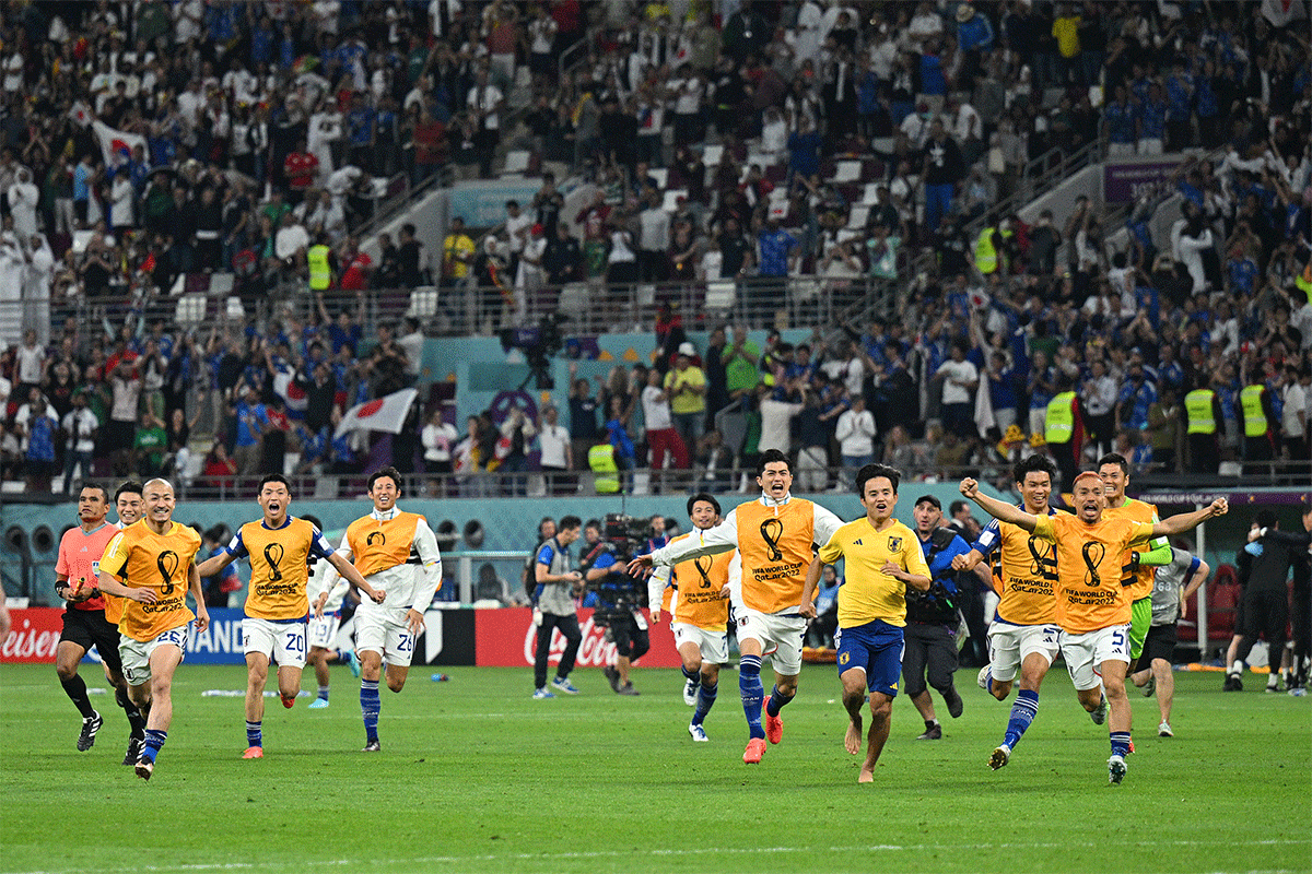 Japan players run on to the pitch to celebrate with their teammates