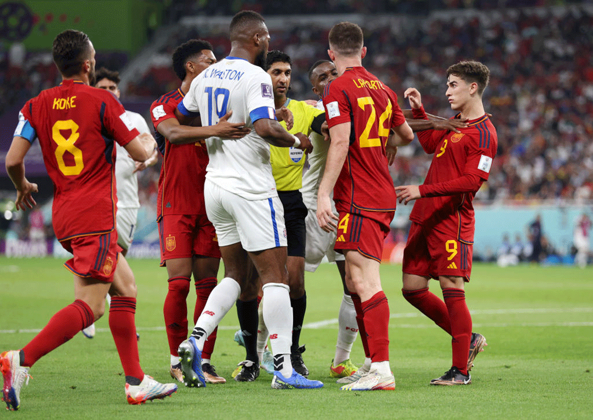 Referee Mohammed Abdulla attempts to break up a scuffle between Spain and Costa Rica players