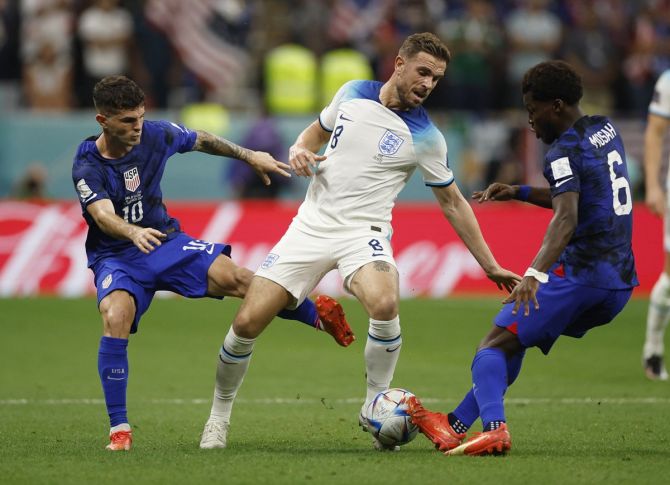 England midfielder Jordan Henderson battles for possession with Christian Pulisic and Yunus Musah of the United States during Friday's FIFA World Cup Group B match, Al Bayt Stadium, Al Khor, Qatar.